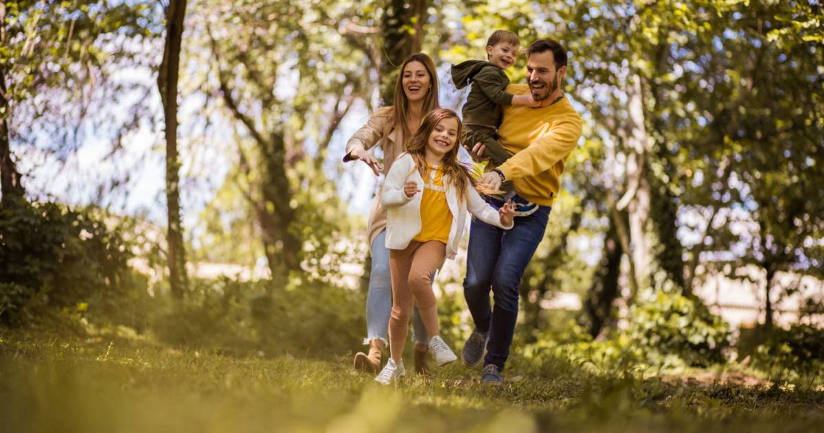 Een vader, moeder en 2 kinderen rennend door het bos