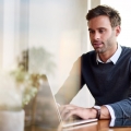 Jonge ondernemer is vanuit huis aan het werk op zijn laptop